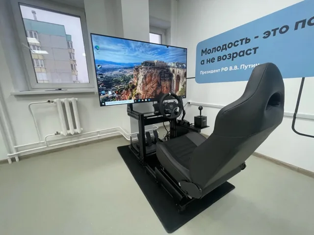 Реальная фотография автосимулятора: кресло, руль, педали, переключатель и экран